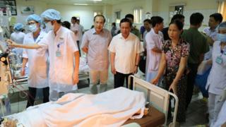 This picture taken on 29 May 2017 shows officials and family members standing next to patients undergoing kidney dialysis in an intensive care unit at hospital in the northern city of Hoa Binh